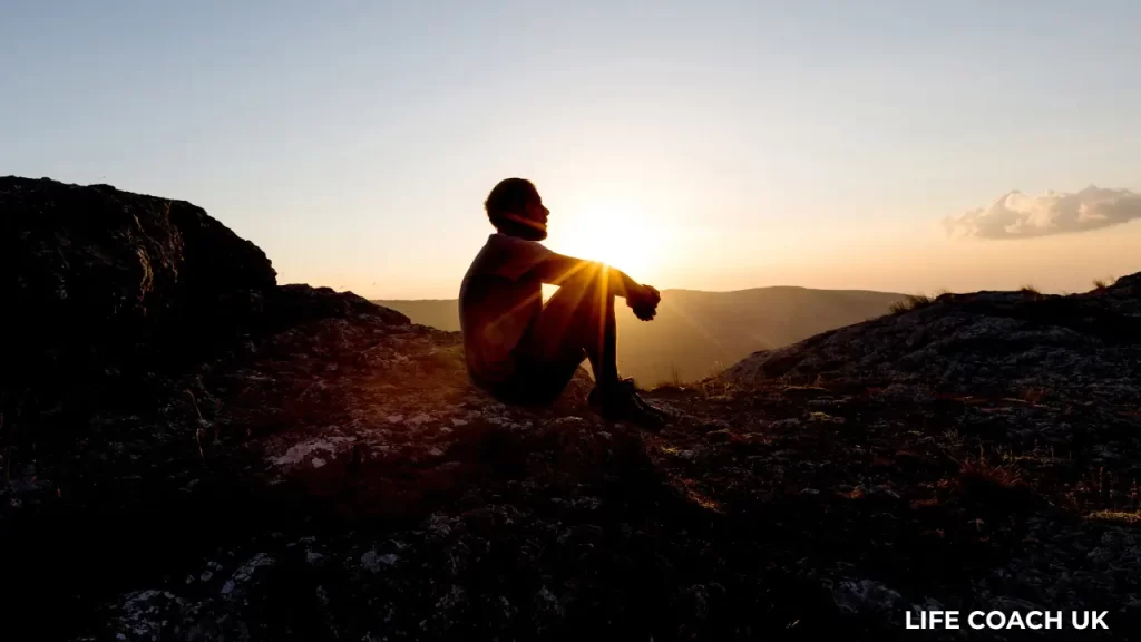 Person sitting alone at sunset, reflecting on life direction and personal clarity